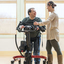 Rifton E-Pacer shown with man walking and therapist assisting and smiling.