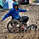 Young man, deep in the mud, but mobile in his FreeWheel Wheelchair Attachment.