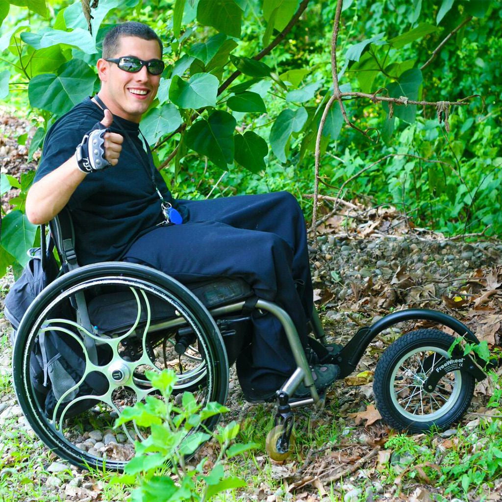 Young man traipsing through the woods in his FreeWheel Wheelchair Attachment.