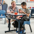 Boy participating in classroom activities with his teacher in the Rifton Compass Chair.