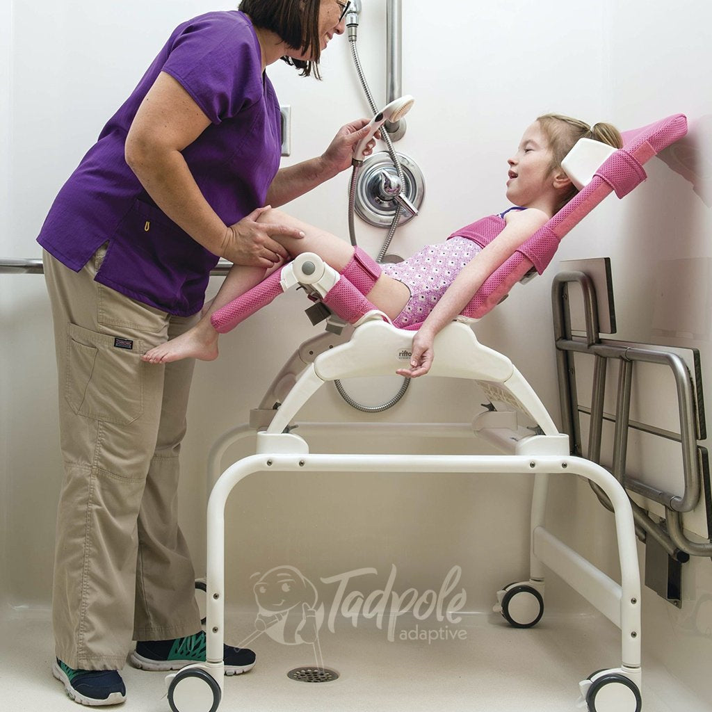 Young girl using Rifton Wave on Shower Stand with helper in roll-in shower.